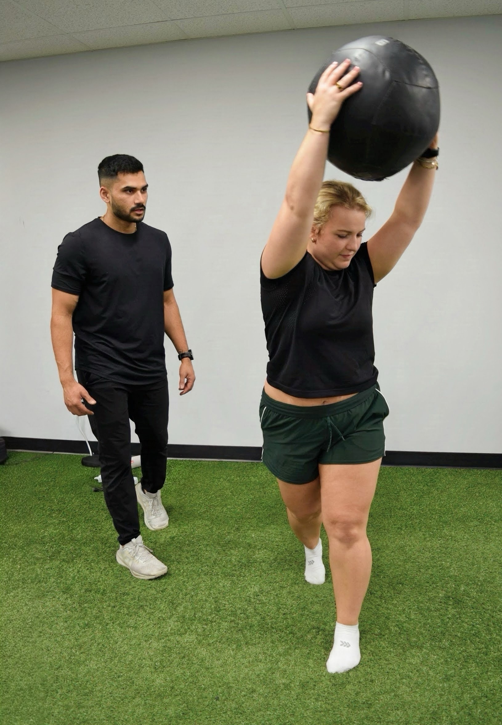 Therapist guiding a patient through a weighted single-leg exercise